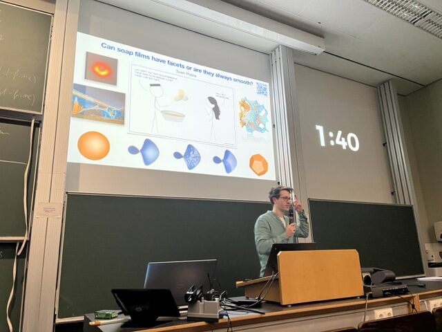 Sven Pistre standing in front of a slide, giving a presentation in a lecture hall.